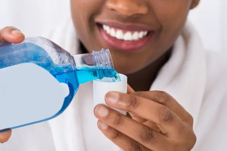 A realistic picture of a lady pouring mouthwash in the cap represnting oral health products